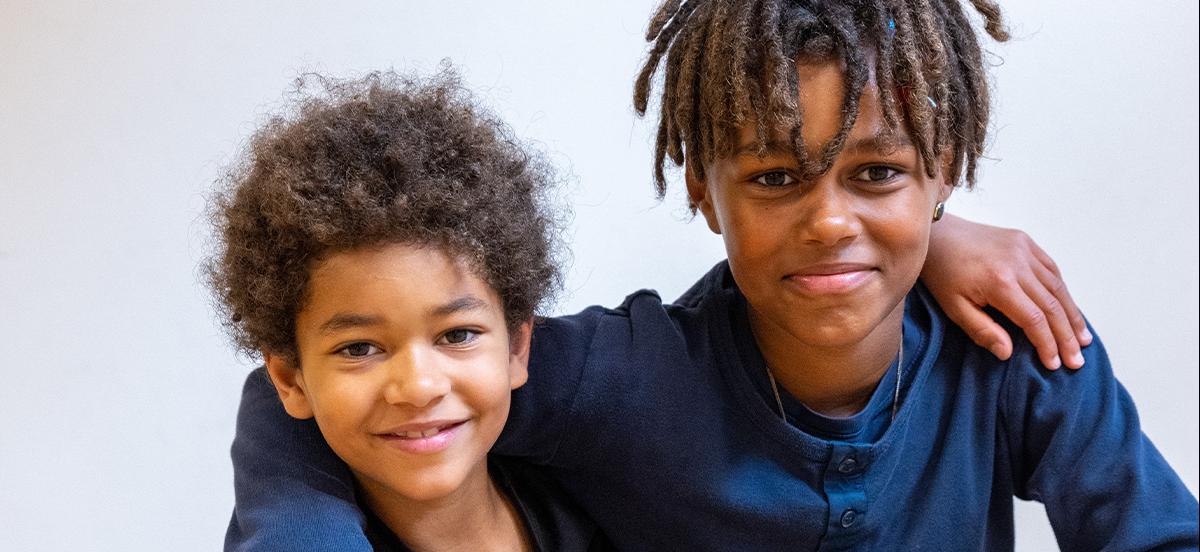 To glade børn som står arm i arm